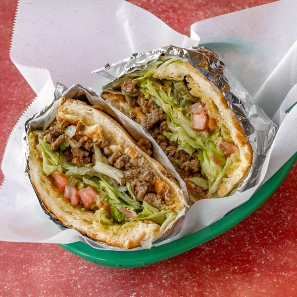 Two halves of a Freedom Burrito, filled with meat, lettuce, and tomatoes, in a green basket.