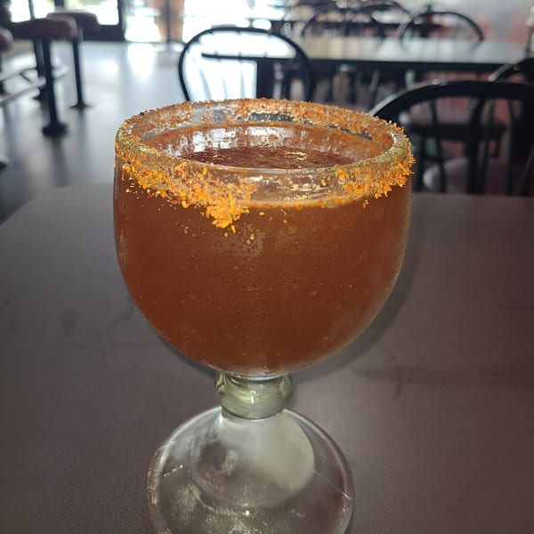A Freedom Burrito michelada in a goblet with a chili-salted rim, on a table inside the restaurant.